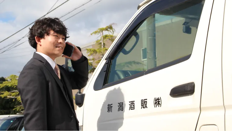車のそばで電話をする男性スタッフの写真