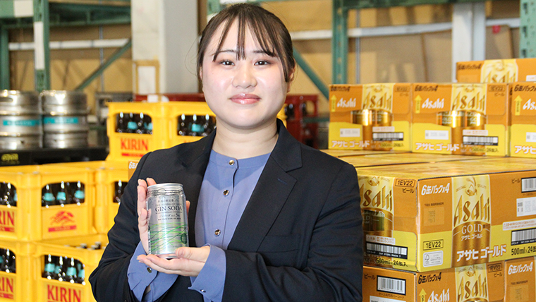 倉庫で商品を持ち笑顔の女性スタッフの写真
