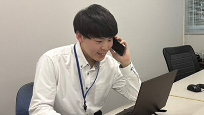 電話対応をしながらPC作業をする男性社員の写真