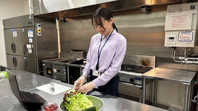 調理設備が整った環境で、食材の盛り付けや品質を確認する女性社員の写真
