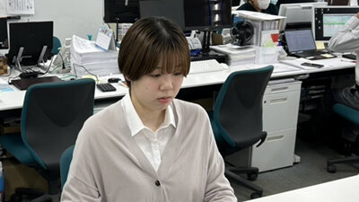 オフィスのデスクにて、落ち着いた表情で事務業務にあたる女性社員の写真