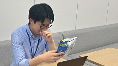 商品パッケージを手に取り、内容を確認する男性社員の写真