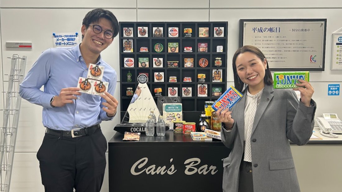 地域の嗜好やトレンドを捉えた商品を持つ笑顔のスタッフ二人の写真